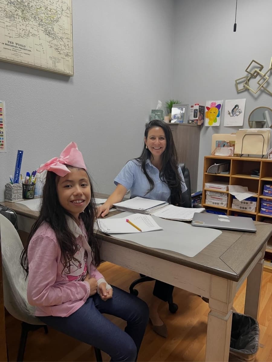 A tutor working one-to-one with a smiling student at a desk